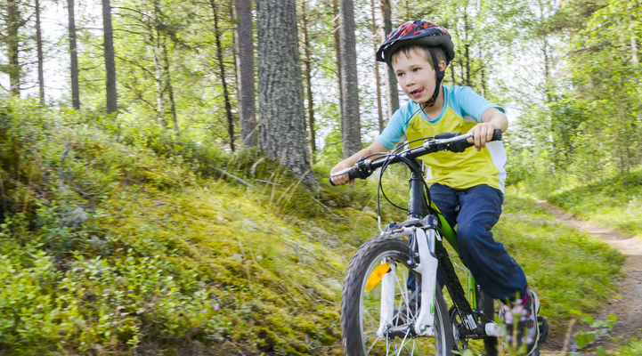 Pojke cyklar på terrängcykel i skogen.
