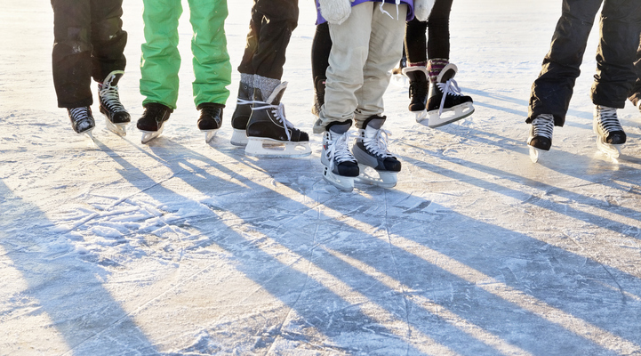Sju personers ben som står på isen iklädda skridskor.
