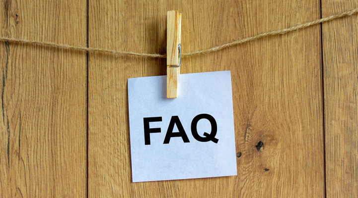 En fyrkantig lapp med texten "FAQ" som hänger i en klädnypa mot en vägg.