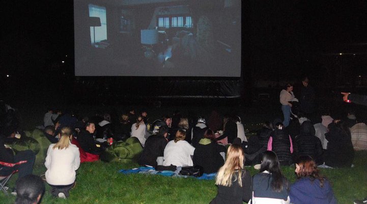 Personer ser på bio utomhus i mörkret