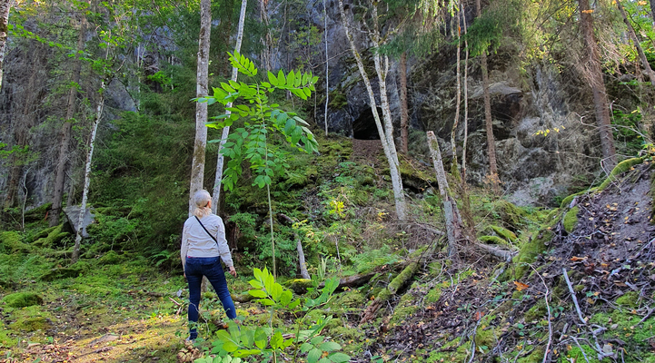 En kvinna i vit jacka står och tittar på ett gruvhål.