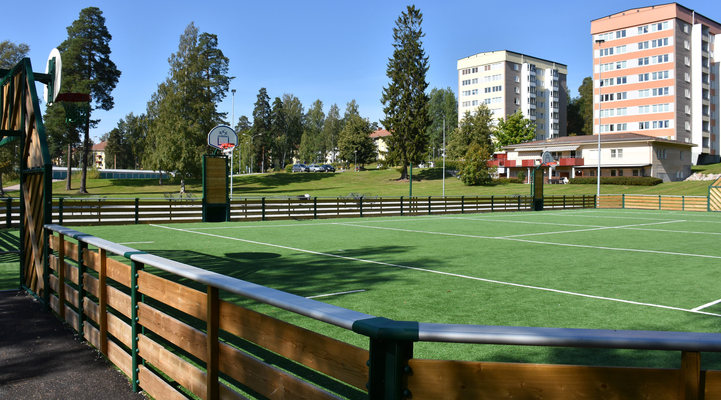 Inhägnad idrottsplats med grönt konstgräs.