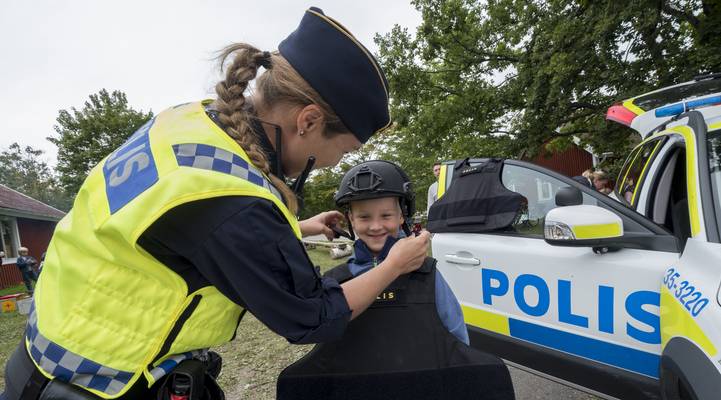 Polis låter ett barn prova polisens skyddsväst.