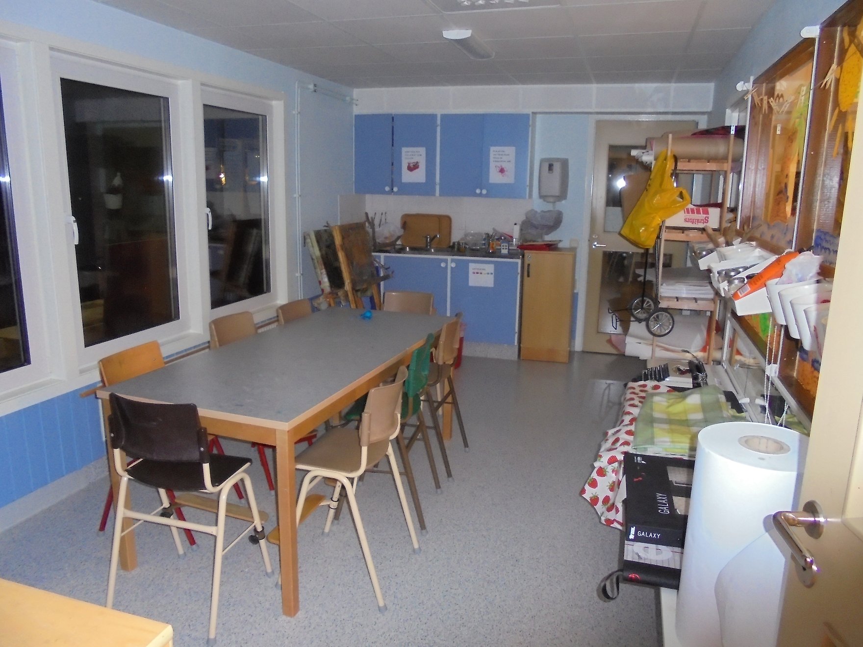 Ett rum för att måla i, ett långt bord med stolar, blå skåpluckor och stafflin